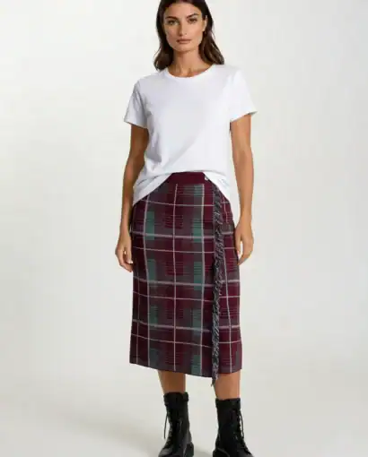 Modella indossa gonna longuette a quadri con dettagli frange e stivaletti neri in pelle.