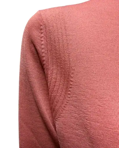 Donna sorridente indossa una maglietta azzurra e jeans, in un ambiente esterno con sfondo arancione e vegetazione.