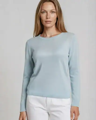 Donna indossa un elegante maglione in cashmere blu chiaro, perfetto per uno stile sofisticato e confortevole.