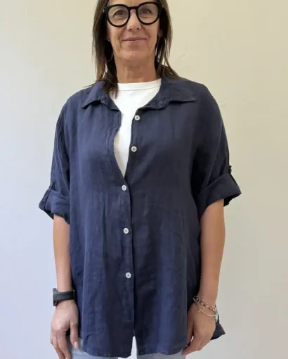Donna con camicia in lino blu, stile casual e elegante, perfetta per ogni stagione. Maglificio Annamaria offre capi di alta qualità, ideali per uno stile raffinato e confortevole.