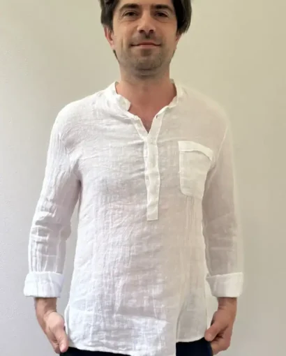 Uomo con camicia bianca in lino, stile casual elegante, in un ambiente neutro, rappresenta la qualità e l'artigianalità del Maglificio Annamaria, specializzato in abbigliamento maschile di alta qualit.