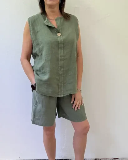 Donna sorridente indossa un outfit estivo in lino verde, composto da top senza maniche e pantaloncini, perfetto per uno stile casual e fresco.