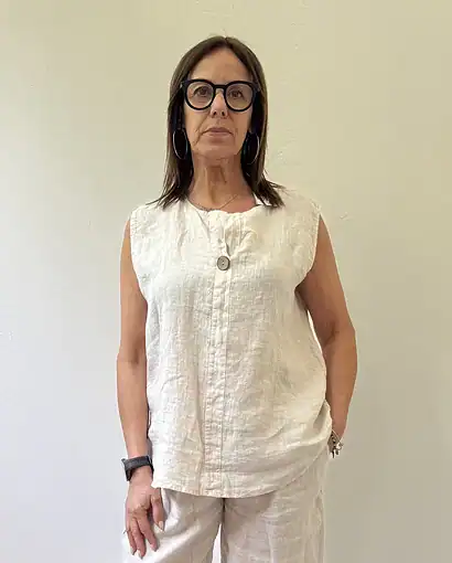 Donna in abbigliamento estivo in lino bianco, con occhiali neri, posa rilassata.