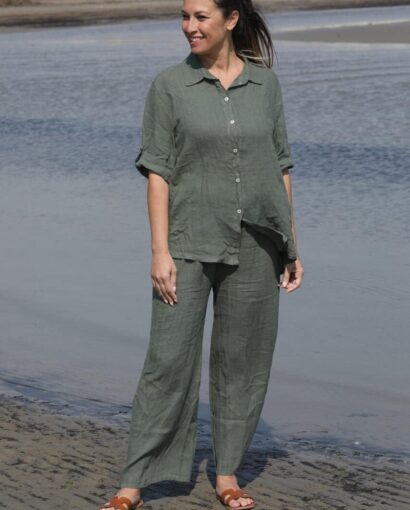Donna sorridente indossa un completo in lino verde, composto da camicia e pantaloni, perfetto per uno stile casual-chic estivo.