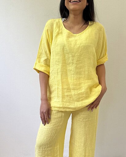 Donna in abbigliamento estivo in lino giallo, vestito comodo e elegante, perfetto per la stagione calda.