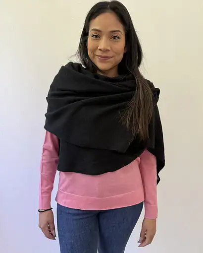 Scialle nero avvolgente indossato sopra un maglione rosa, perfetto per look eleganti e casual. Realizzato con materiali di alta qualità, ideale per la stagione invernale.