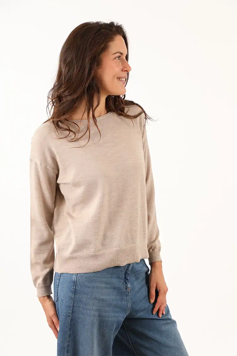 Donna indossa un maglione beige e jeans blu, modello casual, in uno studio con sfondo bianco, ideale per moda autunnale e abbigliamento di qualità Maglificio Annamaria.
