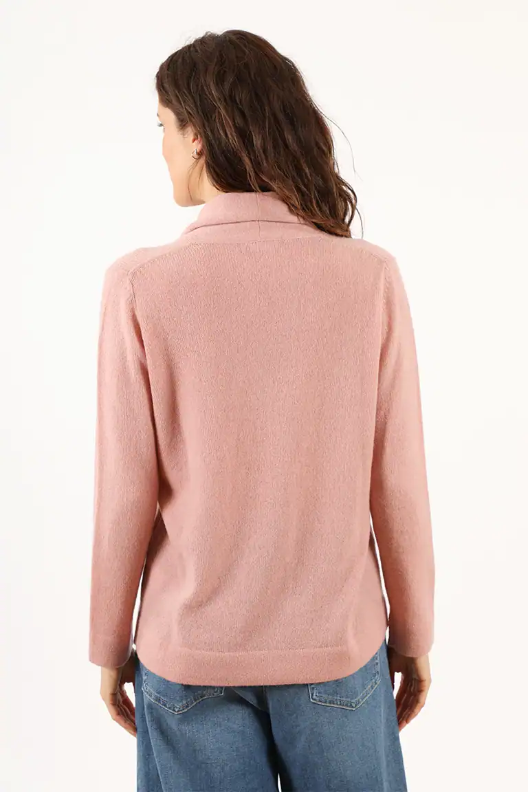 Donna indossa un maglione rosa in lana di alta qualità, perfetto per l'inverno, con un design classico e comodo, ideale per uno stile elegante e casual. Maglificio Annamaria.