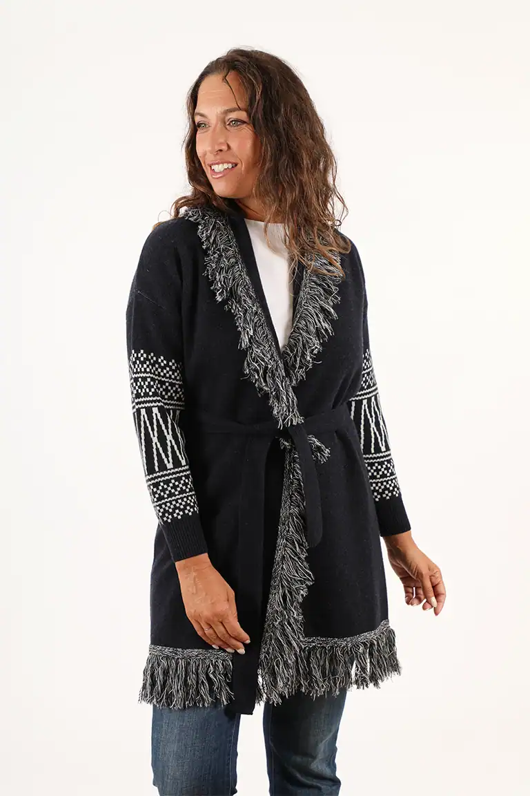 Donna sorridente indossa un cardigan nero con dettagli in pelliccia e frange, perfetto per look eleganti e casual in inverno, da Maglificio Annamaria.