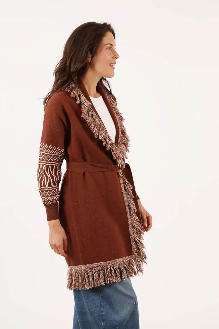 Donna indossa un cardigan marrone con dettagli in pelliccia e motivo a treccia, perfetto per l'inverno, in un ambiente neutro e luminoso.