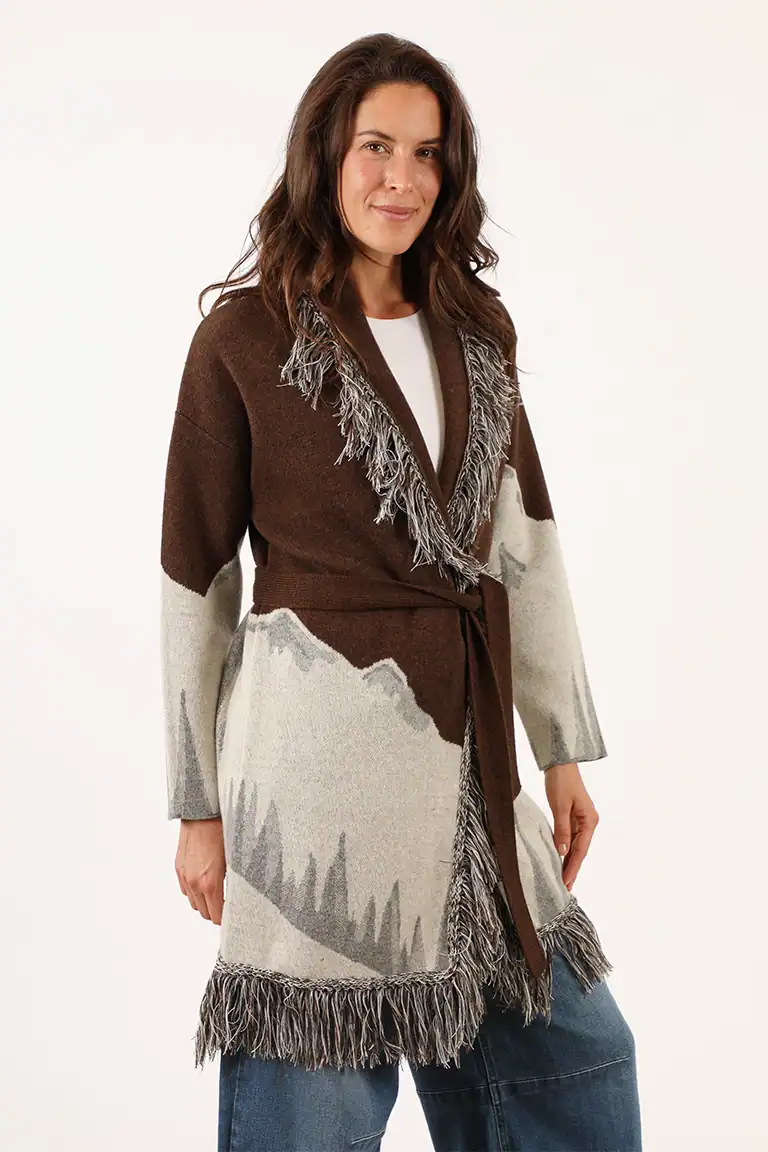 Donna indossa un cardigan in lana marrone e beige con frange, perfetto per look autunnali e invernali, realizzato dal Maglificio Annamaria, specializzato in maglieria di alta qualità.