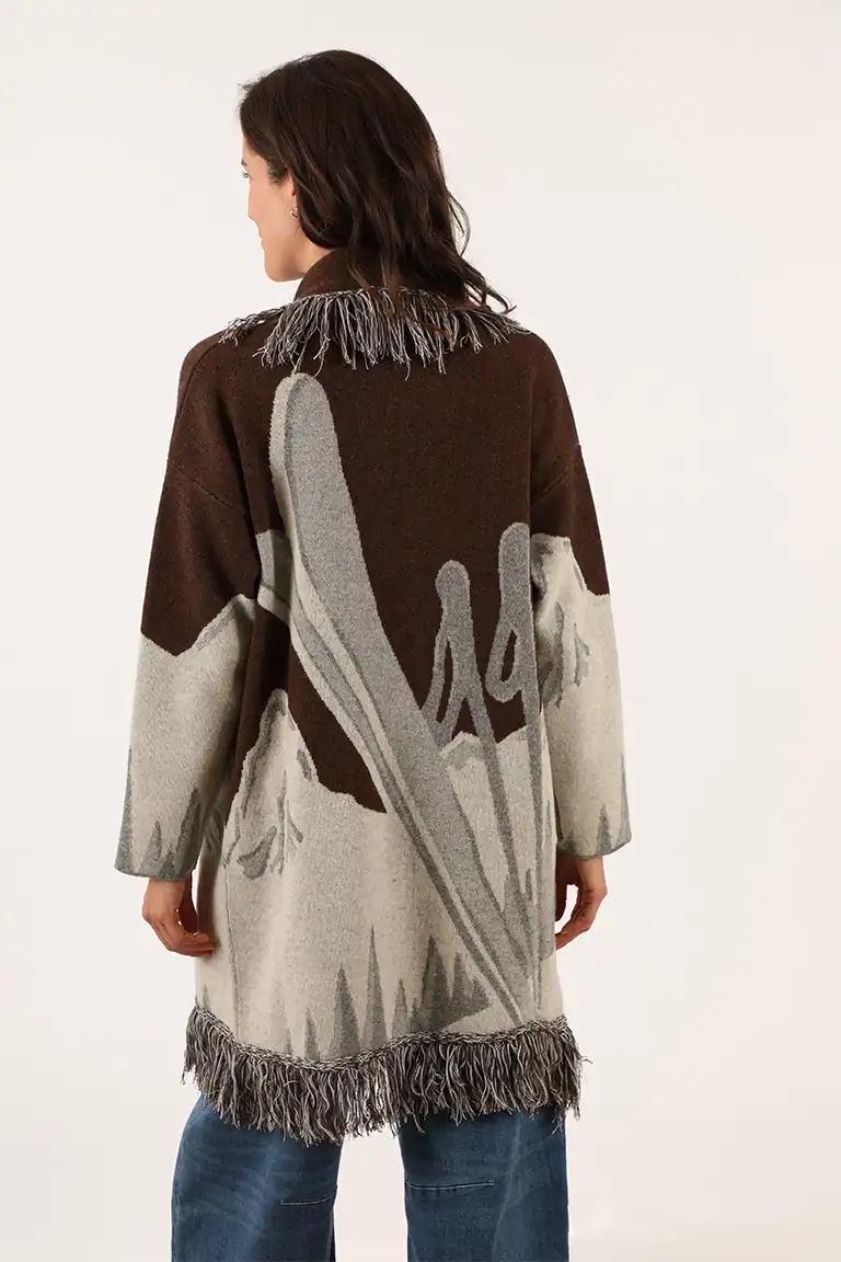 Donna indossa un maglione oversize con motivo paesaggio e frange, realizzato da Maglificio Annamaria, perfetto per stile e comfort invernale.