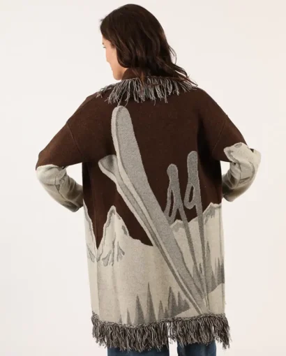 Donna indossa un maglione oversize con motivo astratto in toni marroni, grigi e beige, con frange sul bordo, perfetto per uno stile casual e elegante.