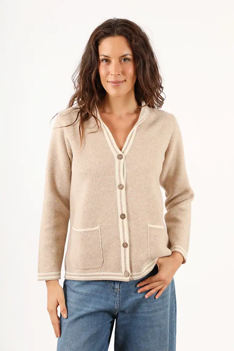 Donna indossa un cardigan beige in lana di alta qualità, perfetto per l'autunno, con tasche frontali e bottoni, in stile elegante e confortevole.