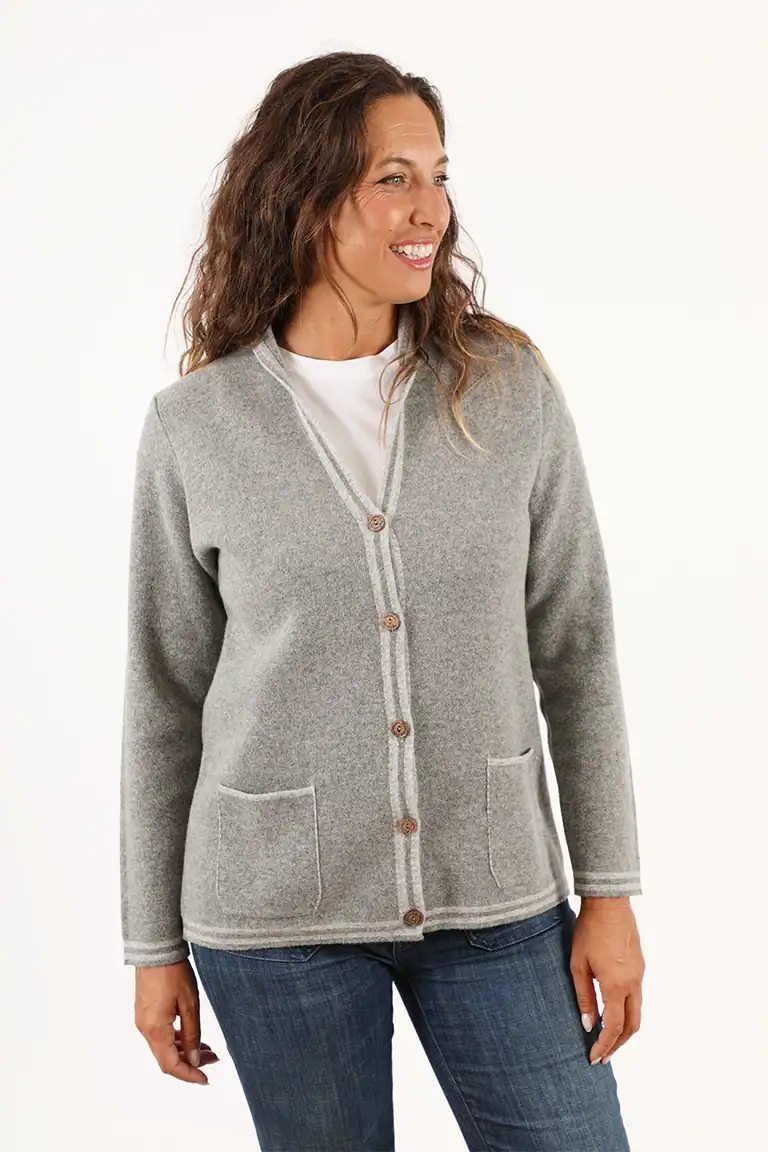 Donna sorridente indossa un cardigan grigio con tasche, abbigliamento elegante e confortevole, perfetto per look casual e autunnali, in un ambiente neutro e luminoso.