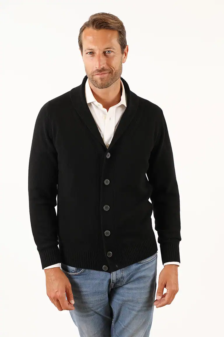 Uomo con cardigan nero, camicia bianca e jeans, stile elegante e casual, in primo piano, per promuovere abbigliamento di qualità da Maglificio Annamaria.