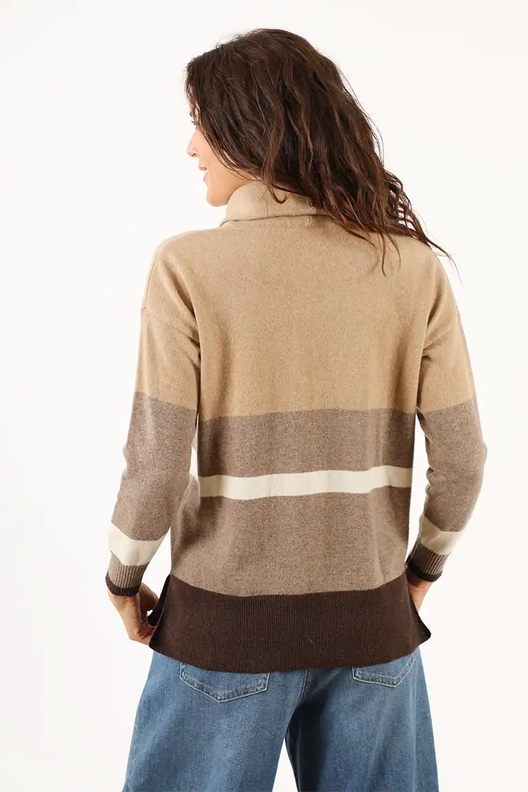 Donna indossa un maglione a righe beige, grigio, bianco e marrone, in stile casual e elegante, perfetto per l'autunno e l'inverno, realizzato dal Maglificio Annamaria.
