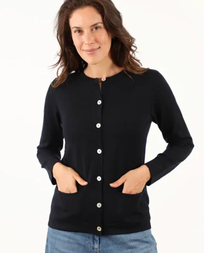 Donna indossa un cardigan nero con bottoni bianchi, stile casual e elegante, perfetto per look autunnali e invernali, in un ambiente luminoso e minimalista.