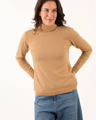 Donna indossa un maglione beige a collo alto e jeans blu, modello casual e elegante, perfetto per look autunnali e invernali, prodotto dal Maglificio Annamaria.