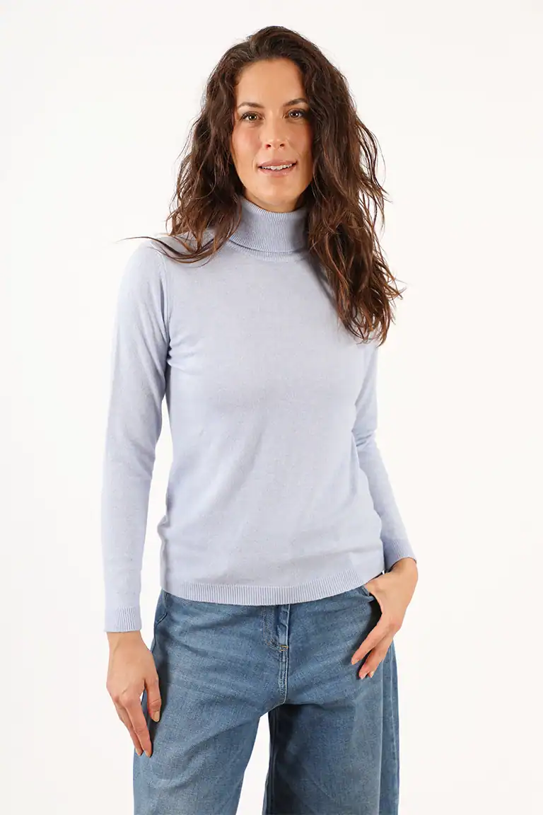 Donna con maglione grigio a collo alto e jeans blu, moda autunnale, abbigliamento elegante e casual, Maglificio Annamaria, produzione italiana di maglieria di alta qualità.
