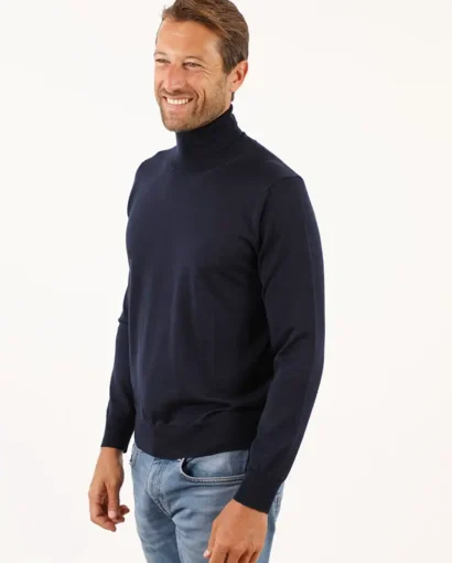 Uomo sorridente indossa un maglione blu navy e jeans chiari, moda elegante e confortevole, ideale per look casual e sofisticati, prodotto dal Maglificio Annamaria.