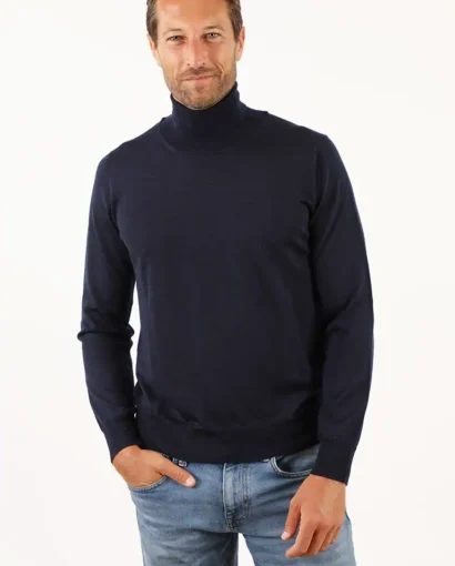 Uomo con maglione blu scuro a collo alto, stile elegante e casual, indossa jeans chiari, sfondo bianco, moda uomo, maglificio Annamaria.