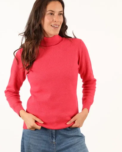 Donna indossa un maglione rosa a collo alto e jeans, moda autunnale e casual, in un servizio fotografico di Maglificio Annamaria, specializzato in maglieria di alta qualità.
