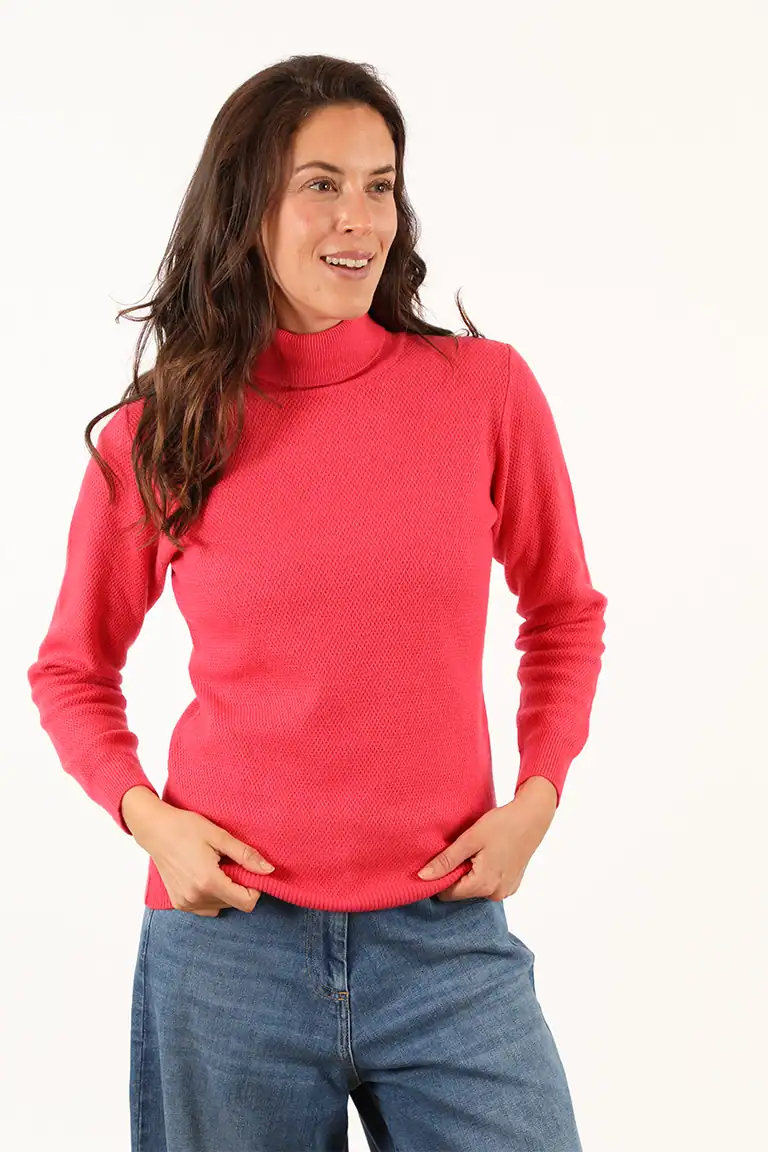 Donna indossa un maglione rosa a collo alto e jeans, moda autunnale e casual, in un servizio fotografico di Maglificio Annamaria, specializzato in maglieria di alta qualità.