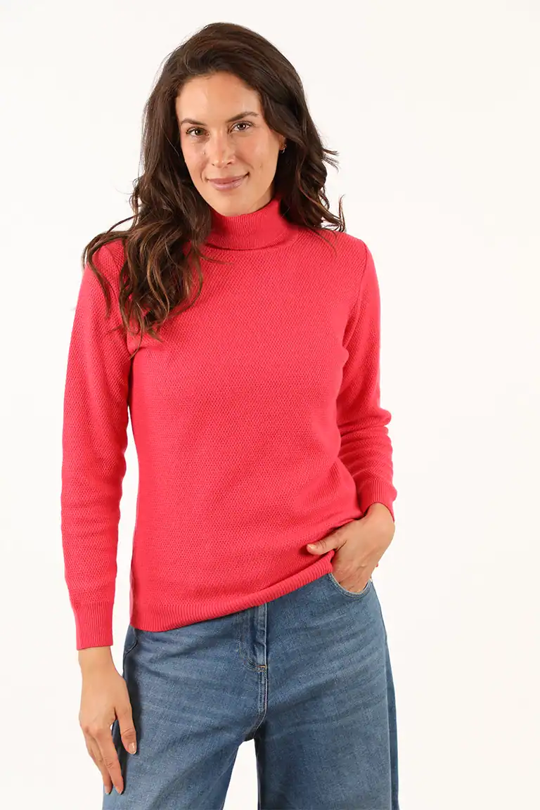 Donna indossa un maglione rosso a collo alto e jeans, rappresentando l'eleganza e la qualità dei maglioni del Maglificio Annamaria, specializzato in maglieria di alta qualità in Italia.