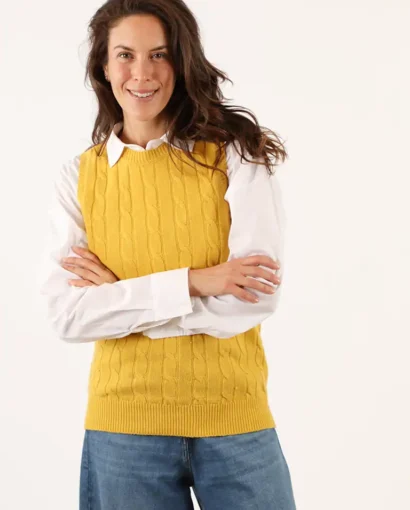 Donna sorridente indossa un maglione giallo a maglia con camicia bianca e jeans, rappresentando l'eleganza e la qualità dei prodotti del Maglificio Annamaria.