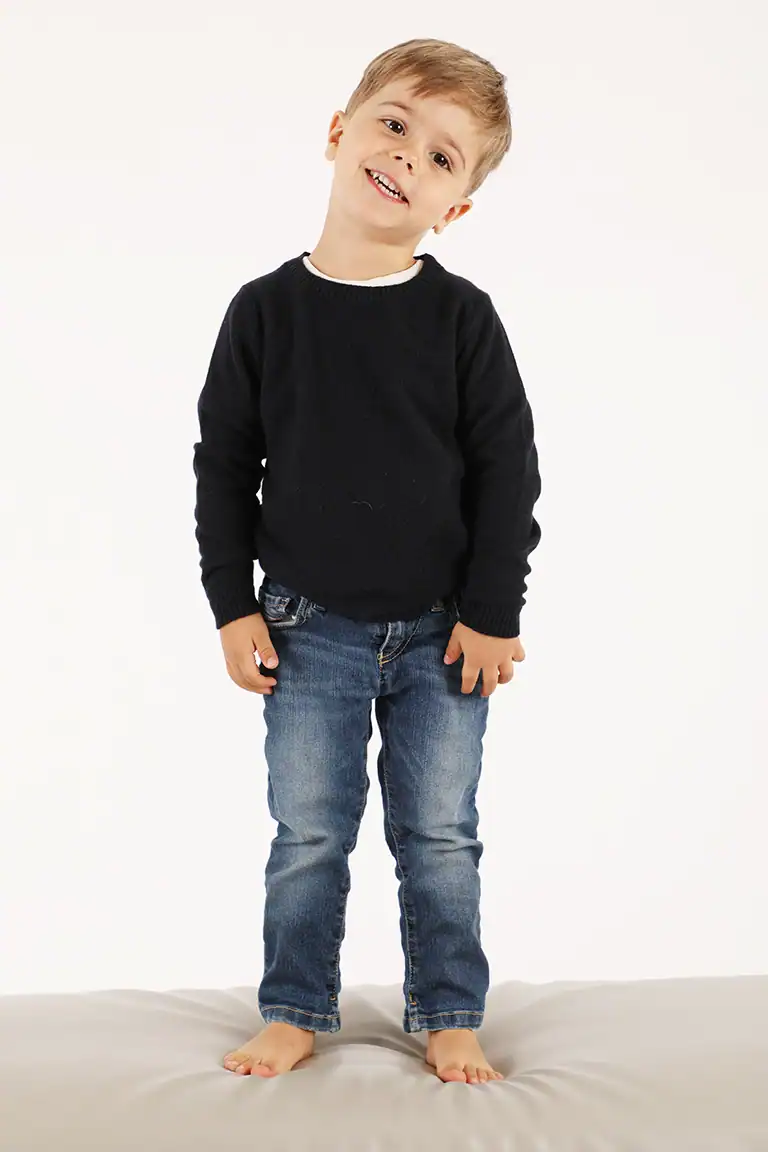 Bambino sorridente con maglione nero e jeans, immagine di moda bambino per Maglificio Annamaria, abbigliamento di qualità per bambini, stile casual e confortevole.