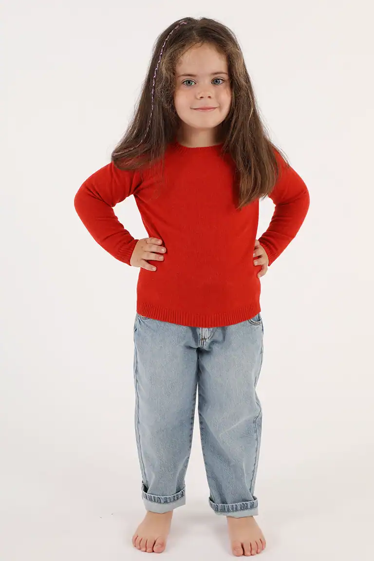 Bambina con maglione rosso e pantaloni di jeans, immagine di moda per bambini, abbigliamento di qualità, Maglificio Annamaria.