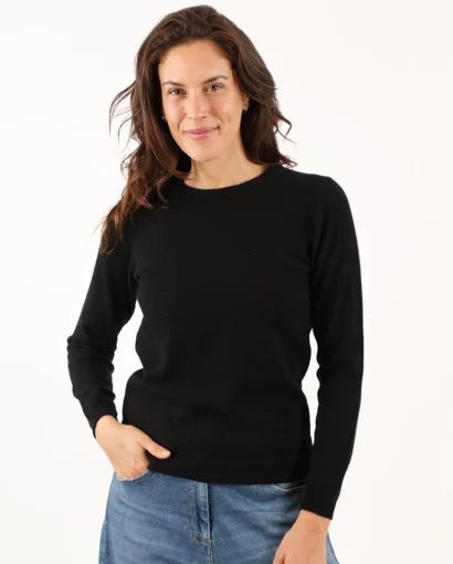 Donna sorridente indossa un maglione beige e jeans, rappresentando l'eleganza e il comfort dei prodotti Maglificio Annamaria per uno stile casual e raffinato.