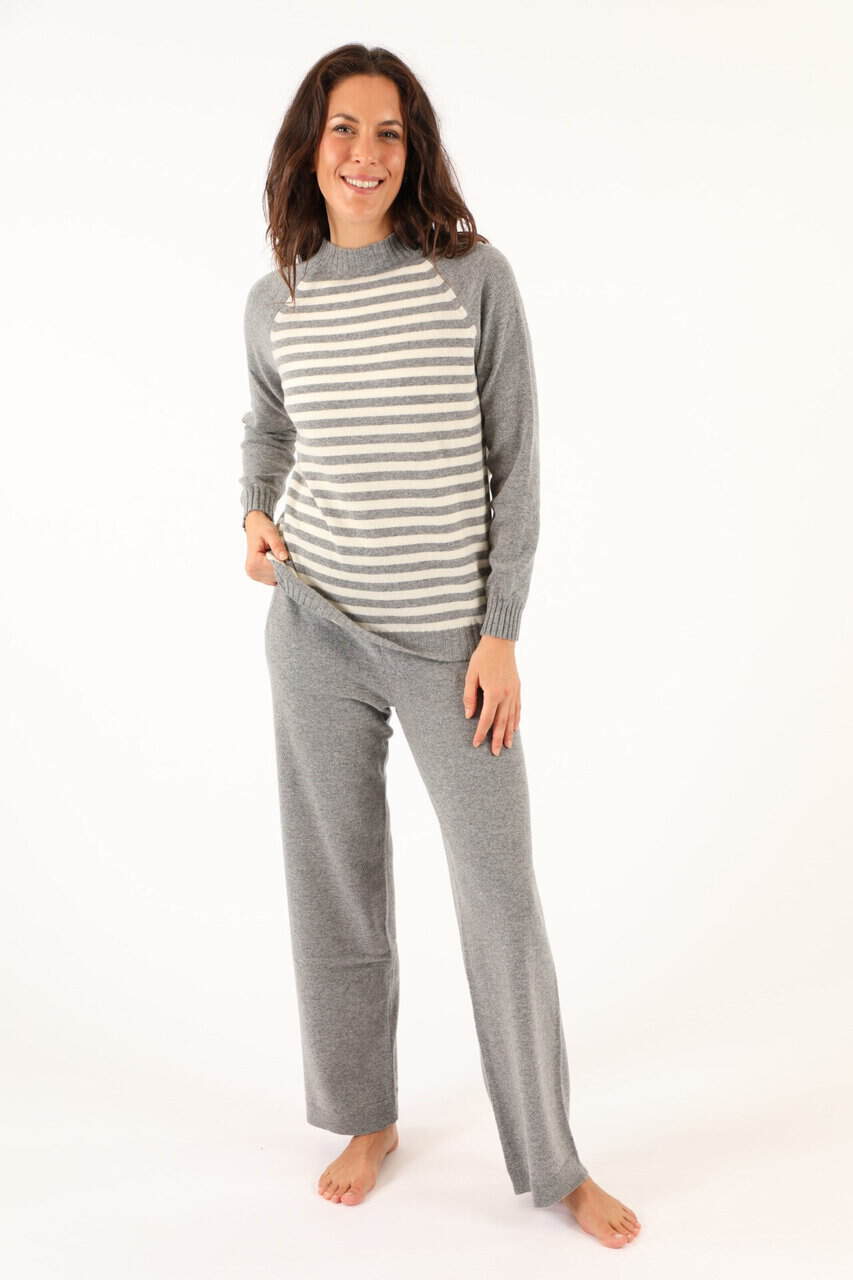 Donna indossa un completo di maglificio Annamaria in tessuto morbido e caldo, ideale per l'inverno, con maglione a righe e pantaloni comodi in grigio.