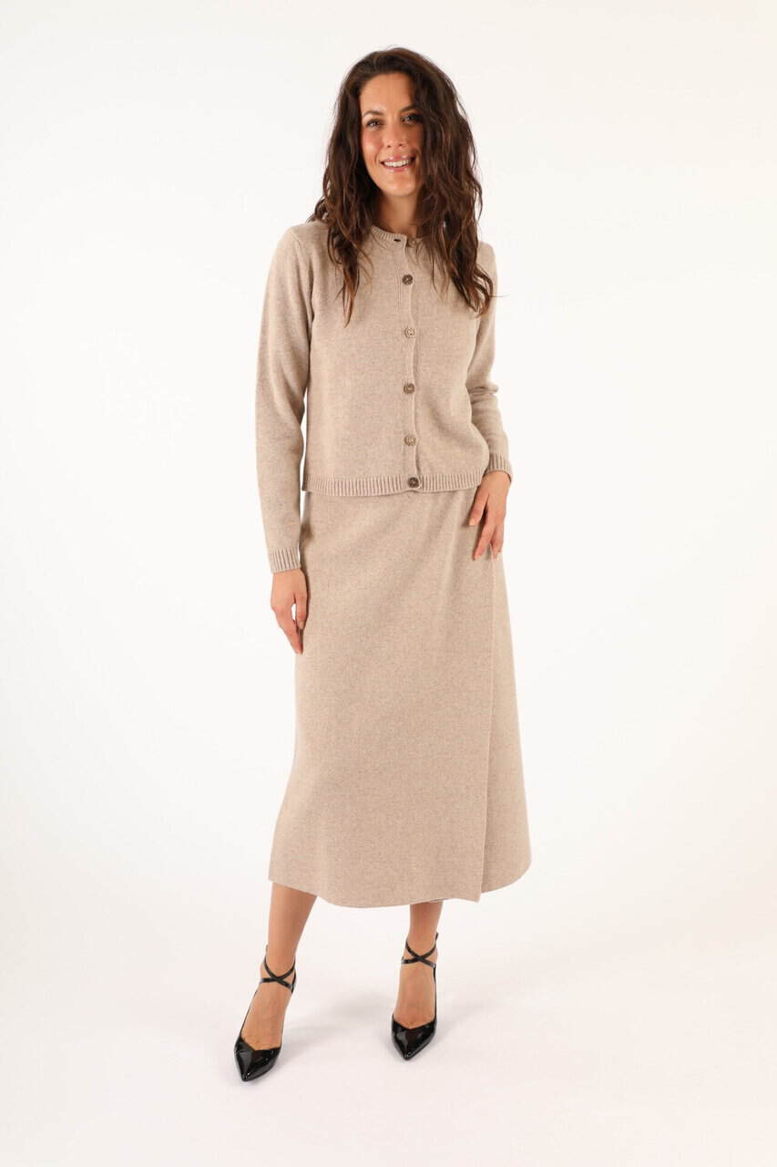 Donna indossa un completo in maglia e gonna in tessuto beige, elegante e confortevole, perfetto per look autunnali e invernali, da Maglificio Annamaria.