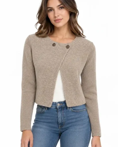 Donna indossa un cardigan beige corto con bottoni, abbinato a jeans blu, in un'immagine di moda elegante e casual di Maglificio Annamaria.