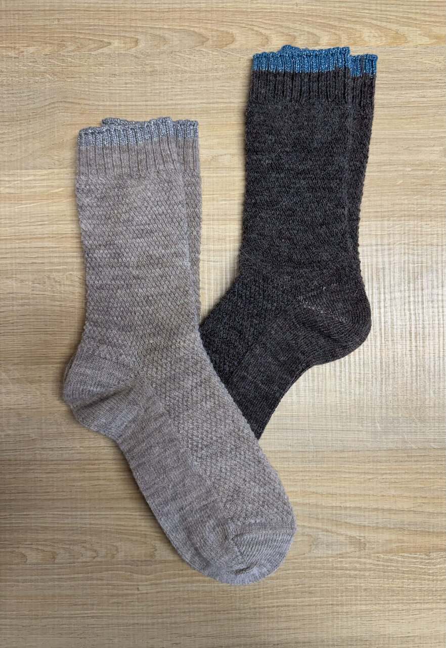 Calze in lana fatte a mano con colori grigio e nero, ideali per l'inverno, realizzate dal Maglificio Annamaria, specializzato in maglieria di alta qualità.